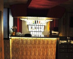 A bar area with a wooden counter, a wine rack, and a cash register.