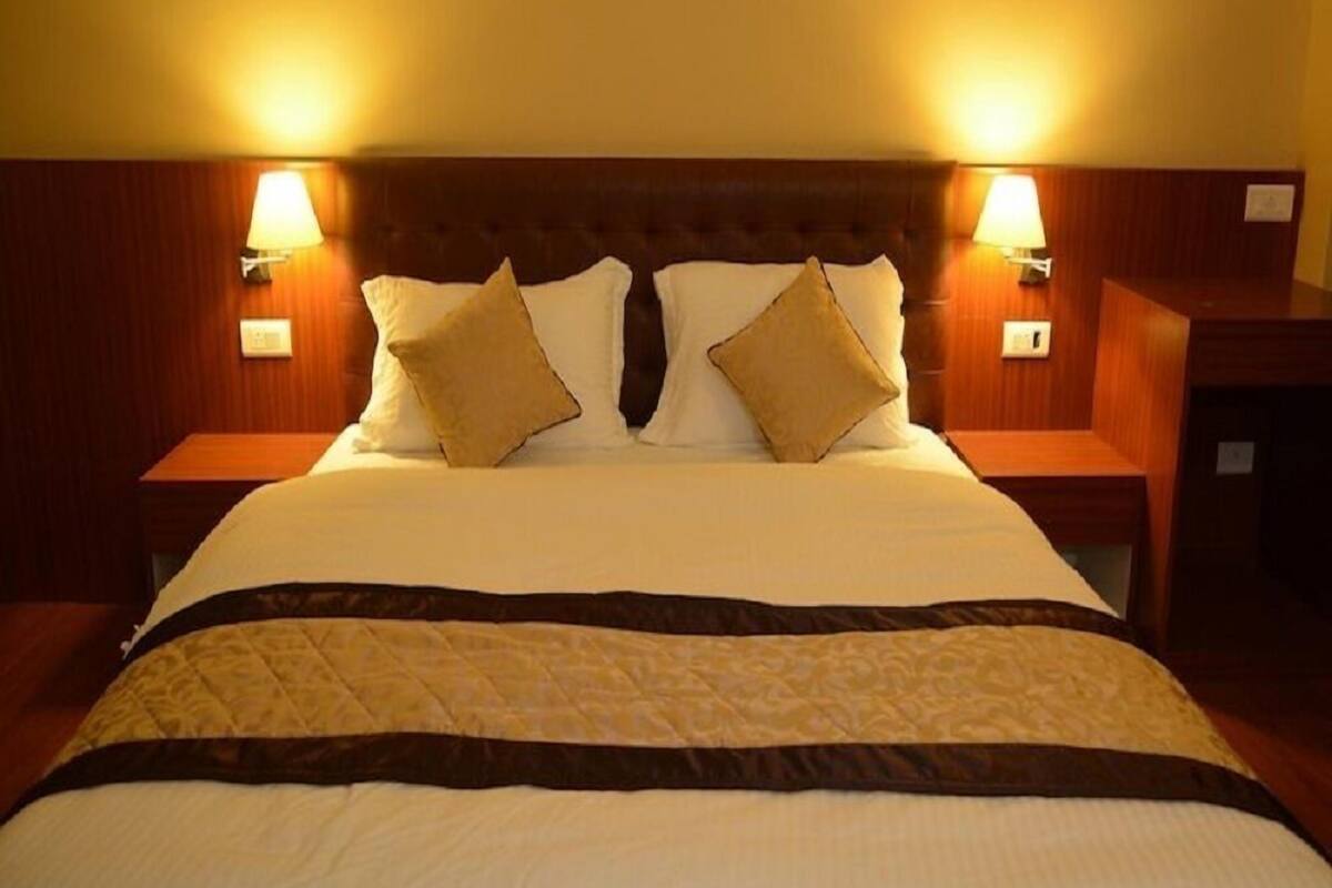 A hotel room with a large bed, two bedside lamps, and a wooden headboard.