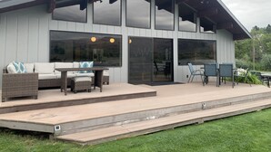 A modern house with a covered patio, large windows, and outdoor furniture.