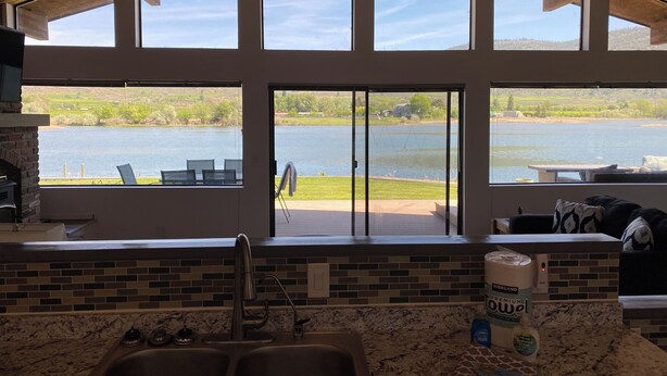 A kitchen with a large window overlooking a lake, a fireplace, and a sink with a tiled backsplash.