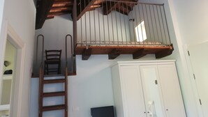 Una escalera con barandilla de madera que lleva a un balcón con baranda de metal.