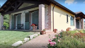 Una casa con porche cubierto, pilares de piedra y un camino de ladrillos que conduce a la entrada.
