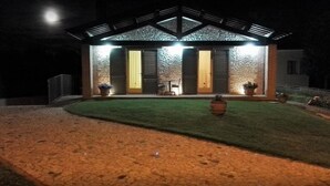Una casa con fachada de piedra, un porche cubierto y un césped bien cuidado.