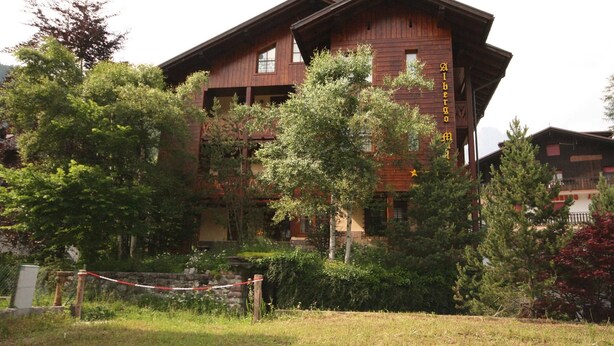 A wooden building with balconies, surrounded by trees and a grassy area. - Casa Gilda (Falcade)