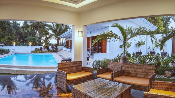 A poolside area with wicker furniture and a marble floor. - Quest Villa (Panglao)