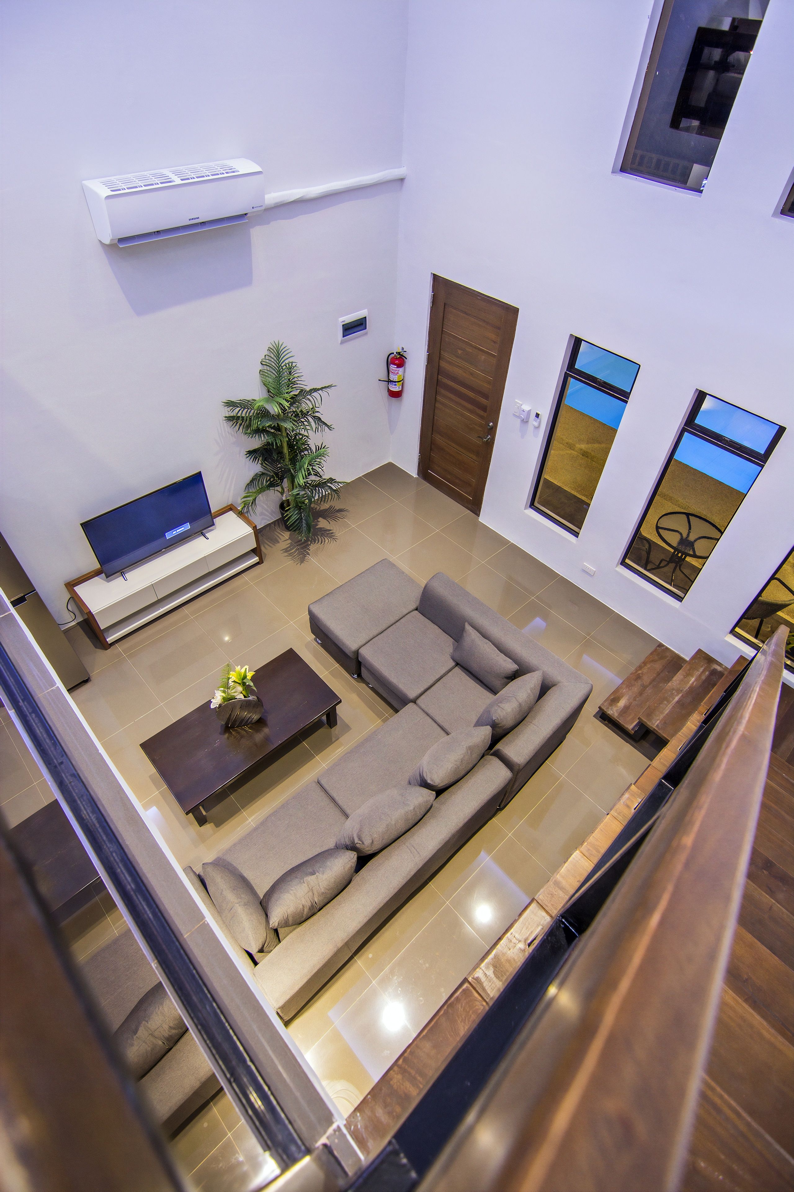 A modern living room with a sectional sofa, a flat-screen TV, a coffee table, and a potted plant.