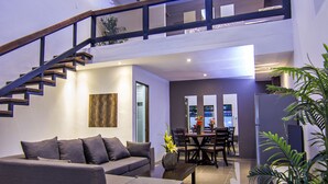 A spacious living area with a modern staircase, a dining table, and a sofa. - Quest Villa (Panglao)