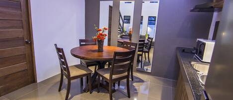 A dining area with a round table, four chairs, and a vase with flowers.