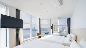 A hotel room with two beds, a TV, a city view, and a small table with chairs.