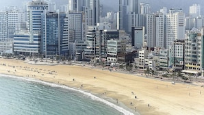 A coastal cityscape with high-rise buildings, a sandy beach, and a clear view of the ocean.