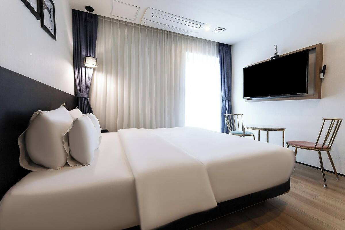 A hotel room with a bed, a TV, a small table, and a chair.