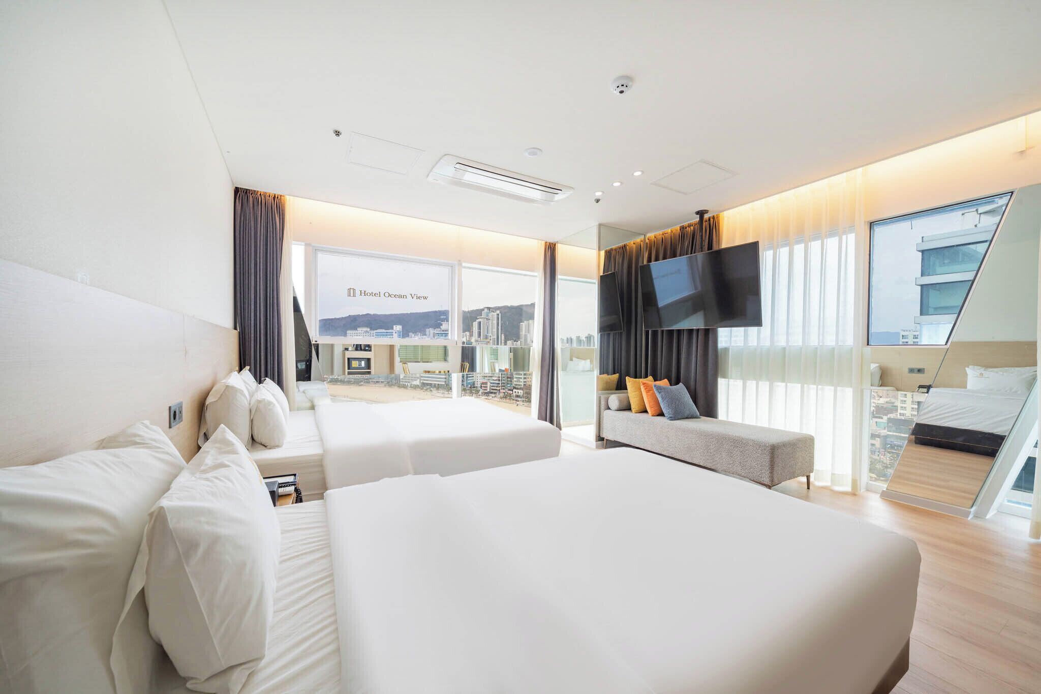 Une chambre d’hôtel avec deux lits, une télévision et un balcon donnant sur la ville.