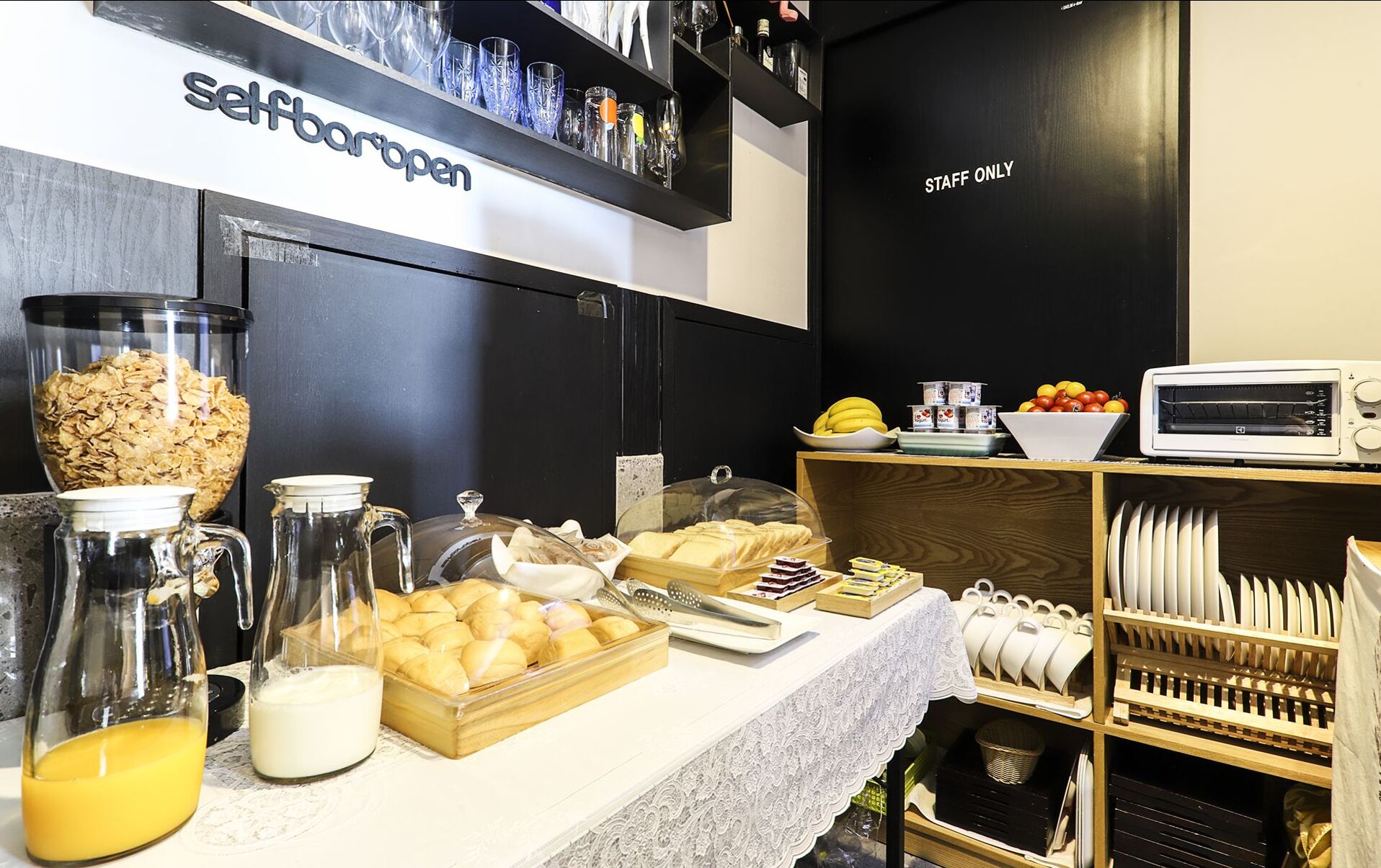 A self-service breakfast bar with cereal, milk, and pastries.