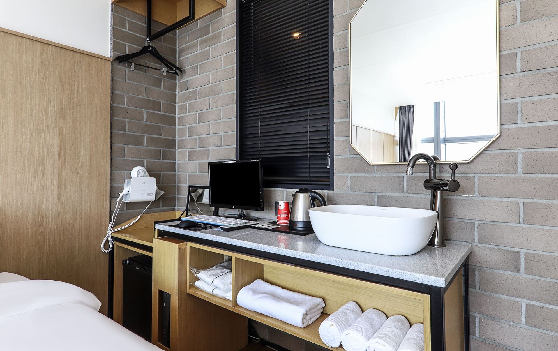 A modern bathroom with a large sink, a mirror, a hairdryer, and a coffee maker.