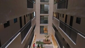 A multi-level atrium with a central courtyard, balconies on each floor, and a person walking in the distance. - Lolong's Listing - Mactan (Lapu-Lapu)