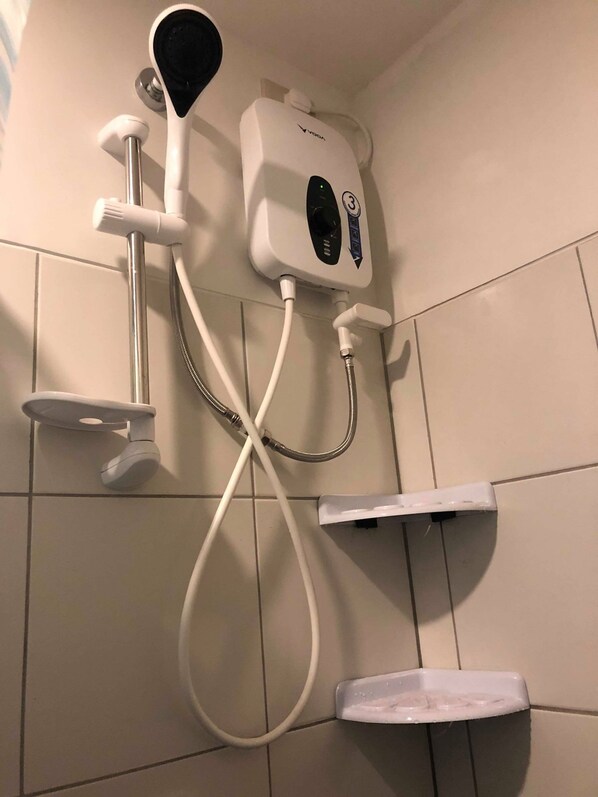 Une douche équipée d’un pommeau de douche à main et d’un panneau de commande fixé au mur.