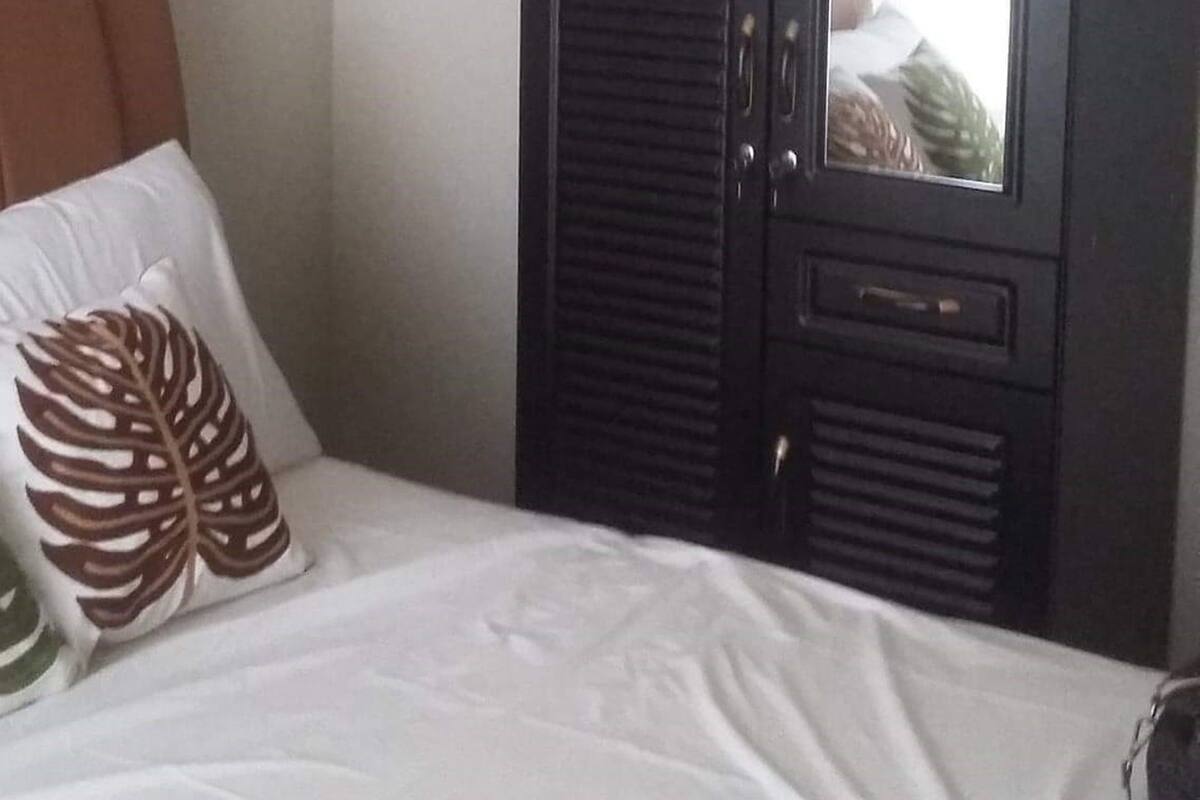 Ein Schlafzimmer mit einem Bett, einem dunklen Holzschrank und einem Spiegel.