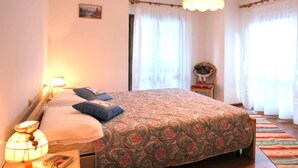 A bedroom with a bed, bedside lamp, and a small table with a book. - Casa Quercia (Falcade)