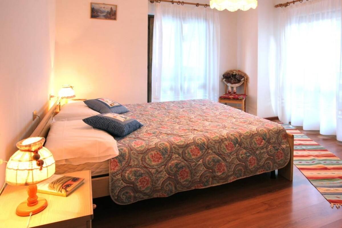 Une chambre à coucher avec un lit, une lampe de chevet et une petite table sur laquelle se trouve un livre.