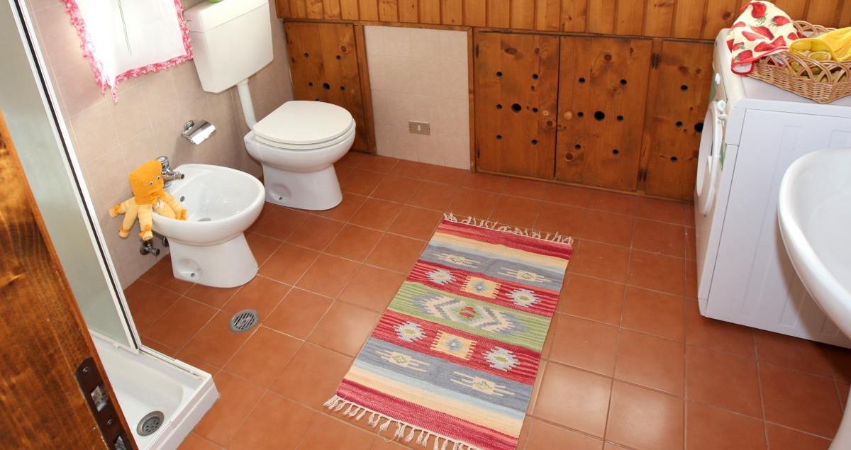 A bathroom with a bidet, toilet, and washing machine.