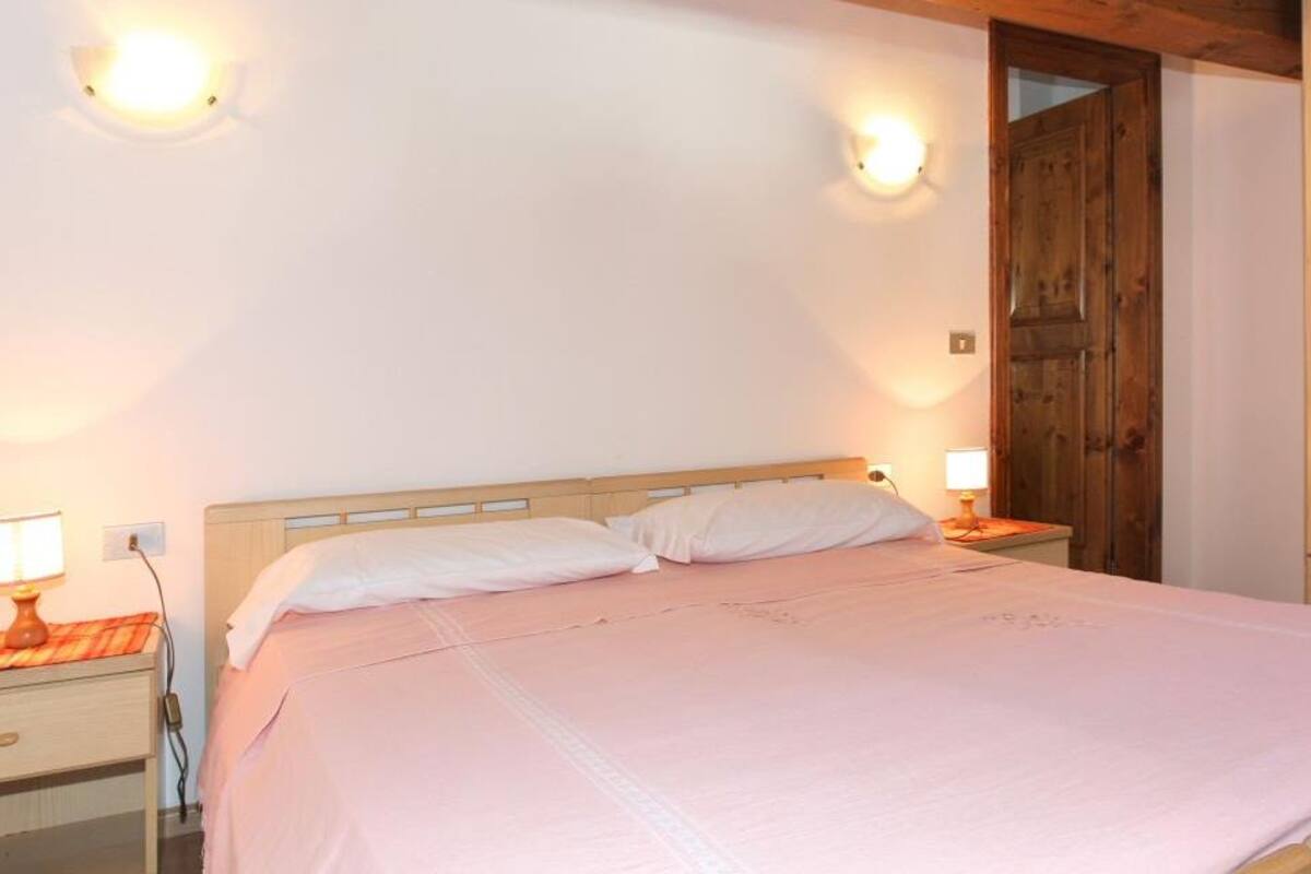 Une chambre à coucher avec un lit en bois, des lampes de chevet et une armoire.