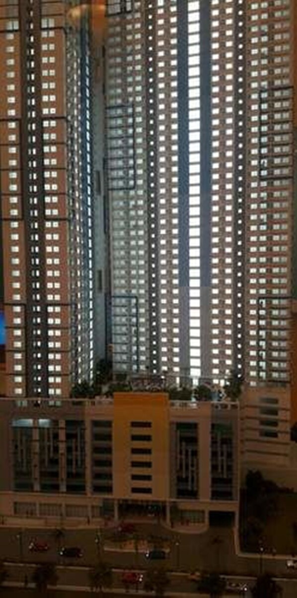 A high-rise building with multiple floors, featuring a central courtyard with a fountain and surrounding greenery.