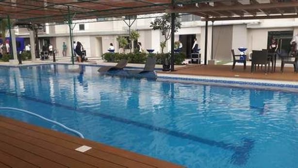 Una piscina interior con una zona de madera para tomar el sol y una sección de estar cubierta.