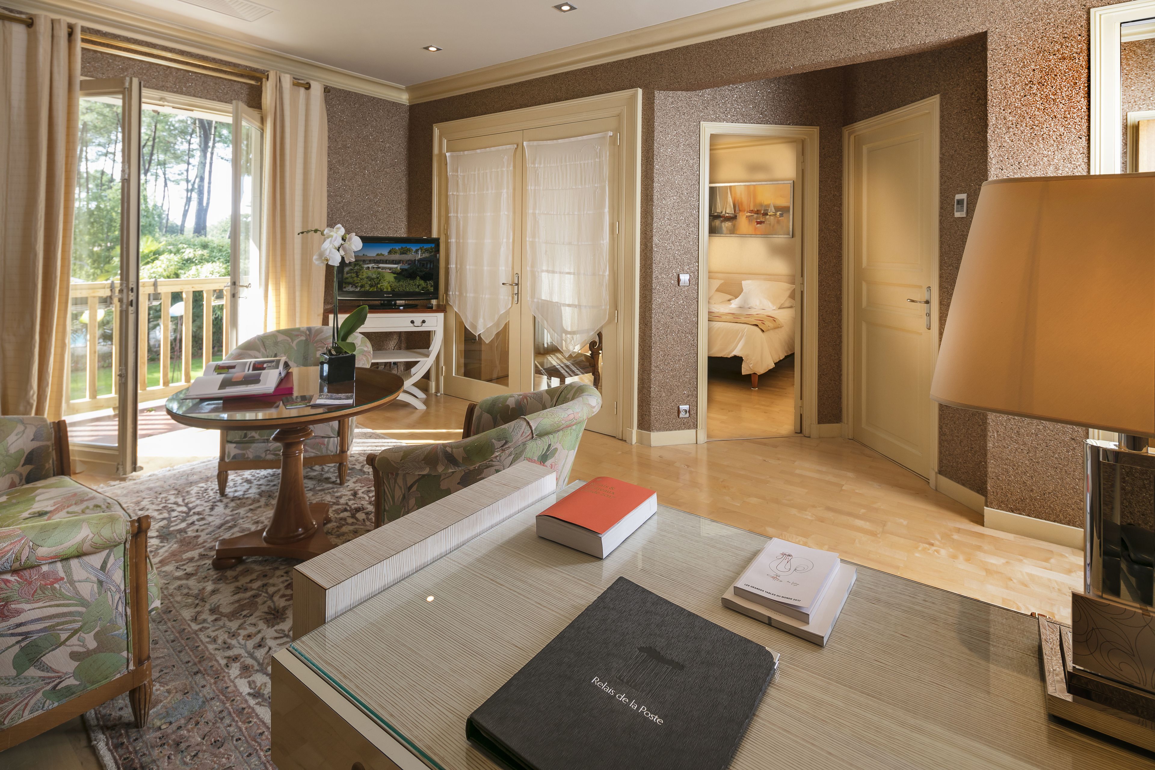 Habitación de hotel con una mesa de comedor, sillas, un sofá, un televisor y una cama.