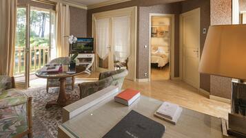 Habitación de hotel con una mesa de comedor, sillas, un sofá, un televisor y una cama.