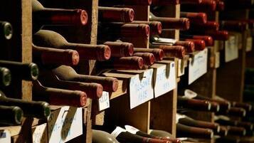 Une cave à vin avec des rangées de bouteilles de vin disposées sur des étagères en bois, chacune portant une étiquette indiquant l’année et le millésime.
