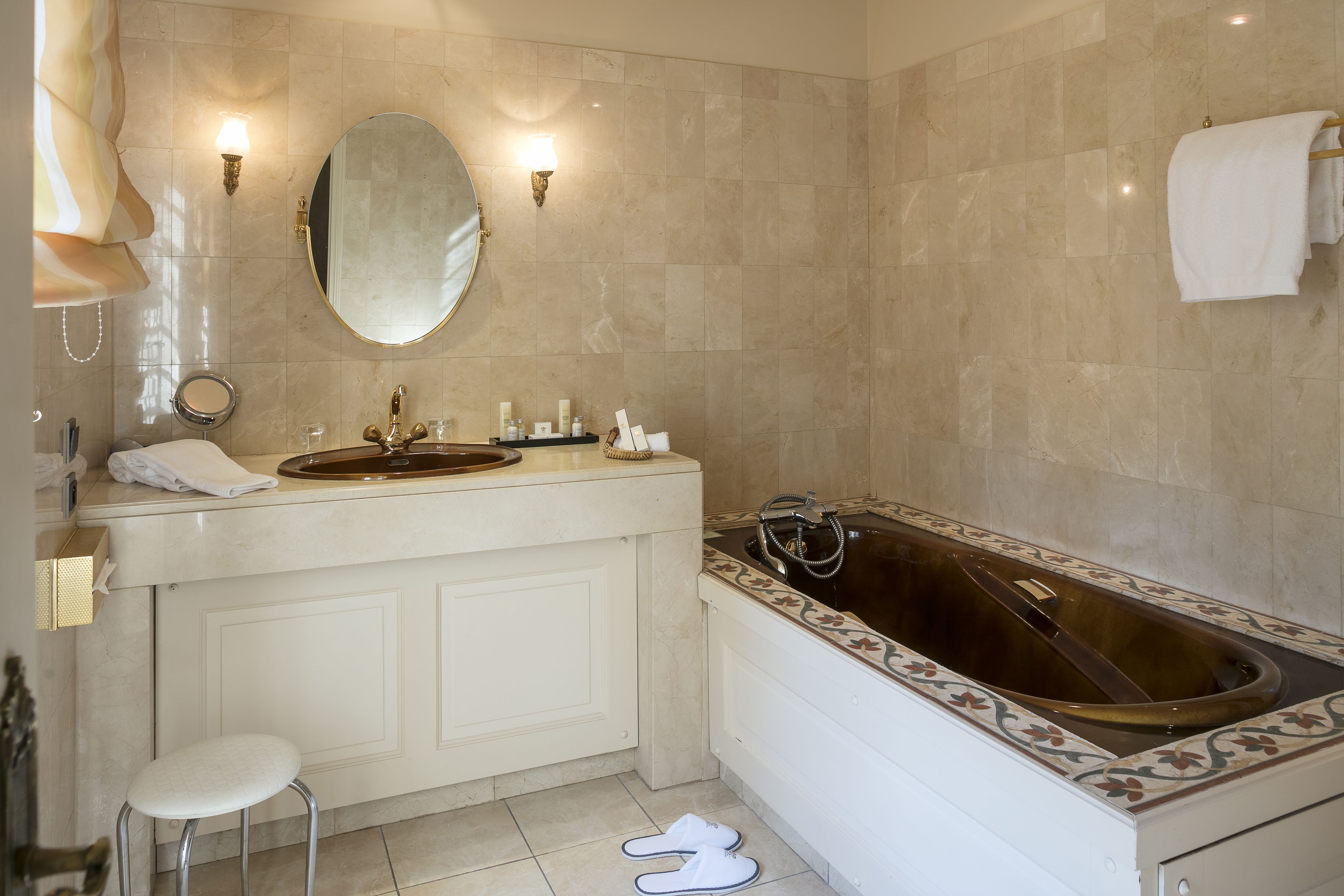 A bathroom with a bathtub, a sink, a mirror, and a stool.
