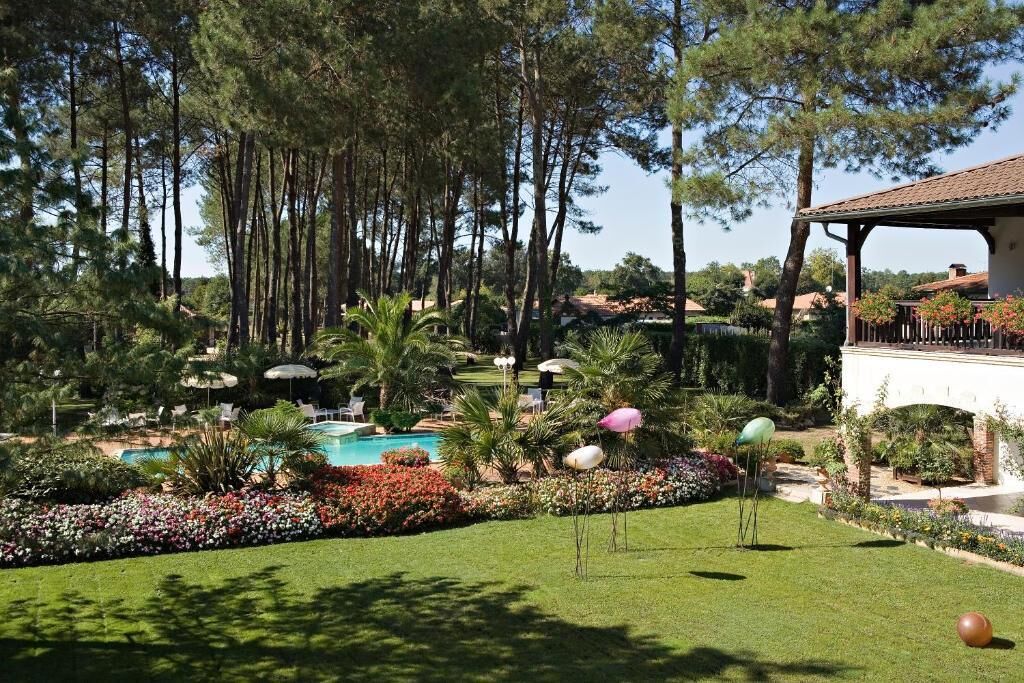 A pool surrounded by a well-maintained garden with various plants and flowers.