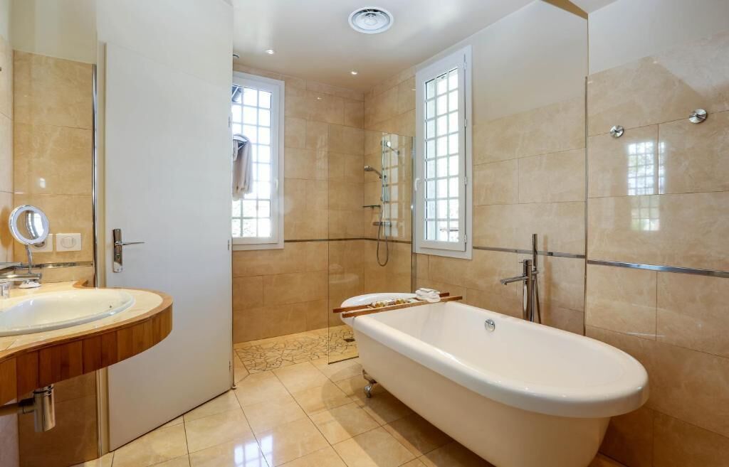 A bathroom with a freestanding bathtub, a sink with a wooden vanity, and a glass shower enclosure.