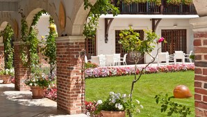 A courtyard with brick columns, white chairs, and flower beds. - LE RELAIS DE LA POSTE (Magescq)