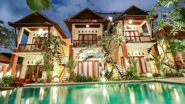 A resort with multiple buildings, a swimming pool, and lush greenery. - Mina Pelasa Hotel and Resto (Legian)