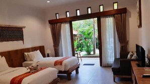 A hotel room with two beds, a desk, a chair, and a television. - Mina Pelasa Hotel and Resto (Legian)