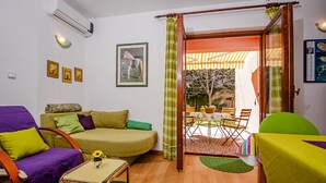 A cozy living room with a sofa, armchair, and a small table with a vase of flowers. - Apartments Aja and Stefy (Rovinj)