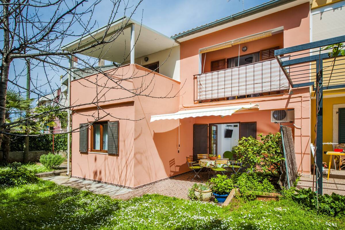 A two-story house with a balcony, a covered patio, and a garden area.
