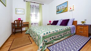 A bedroom with a bed, a desk, a chair, a nightstand, and a window with curtains. - Apartments Aja and Stefy (Rovinj)