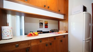Een keuken met houten kastjes, een witte koelkast en een aanrecht met fruit en een mand.