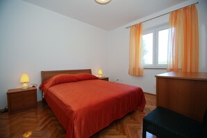 A bedroom with a bed, two bedside tables with lamps, a wooden desk, and a window with curtains. - Apartments Villa Marijeta (Dubrovnik)