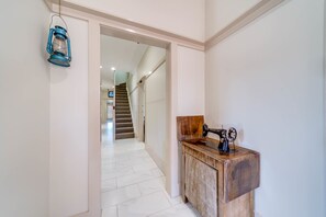 A hallway with a wooden cabinet and a sewing machine, leading to a staircase. - Marulan Stayz (Marulan)