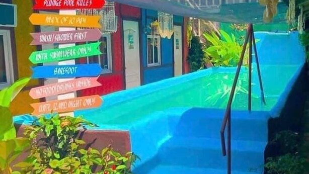 A pool area with a sign listing amenities such as a plunge pool, towel service, and a bar. - Sun Valley Inn - Hostel (El Nido)