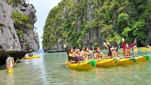 A group of people in yellow canoes on a calm body of water surrounded by rocky cliffs and lush greenery. - Sun Valley Inn - Hostel (El Nido)