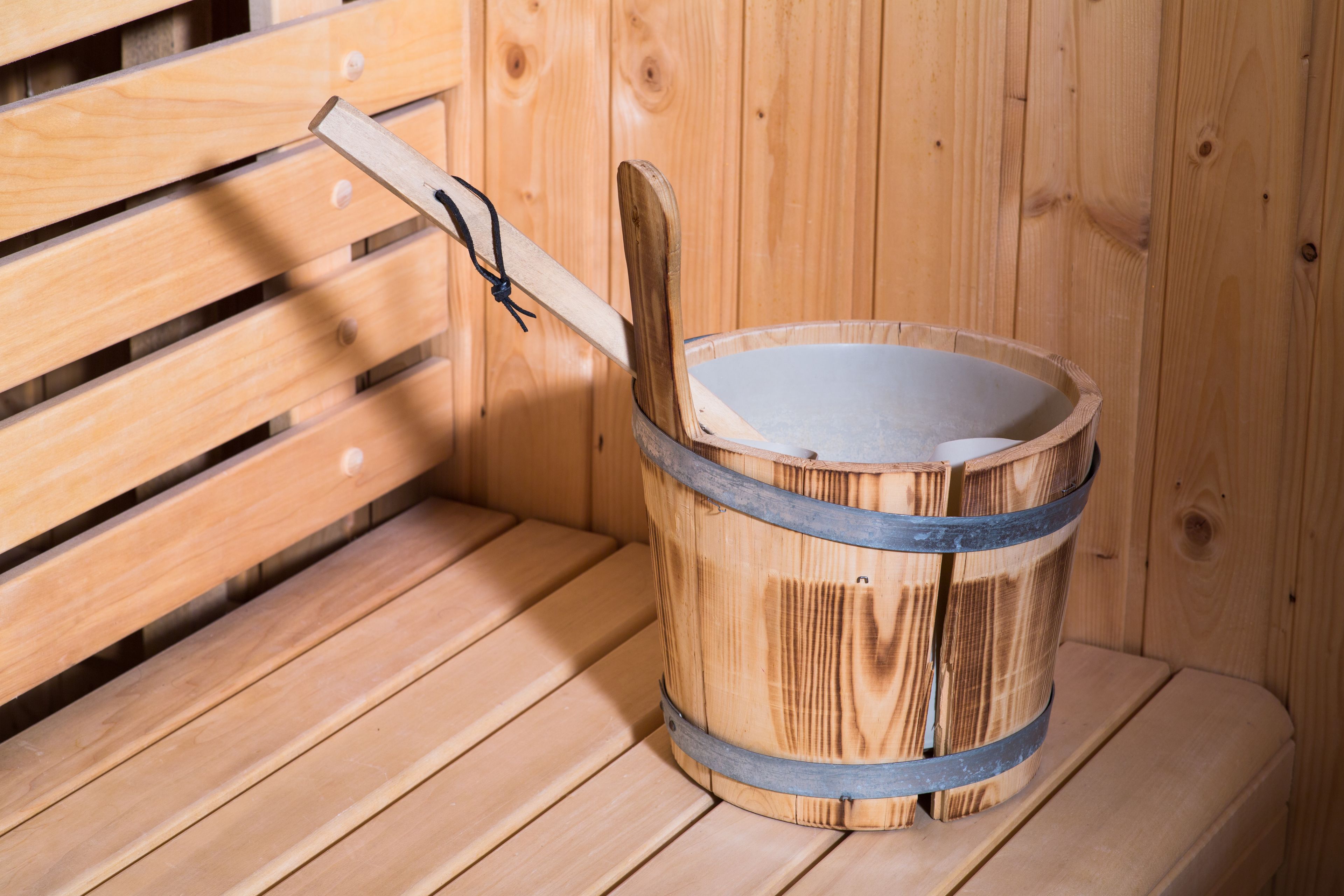 Una sauna in legno con una panca di legno e un catino con manico in legno.