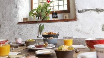 A rustic breakfast table with various breakfast items, a window with a view, and a brick ceiling.