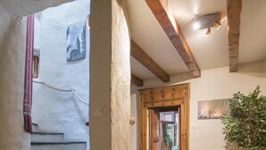 Ein Flur mit Holzbalken, einer Treppe und einer Tür zu einem weiteren Raum.