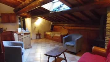 Un acogedor cuarto ático con techo inclinado, una mesa de madera, un sofá, una silla y una chimenea.