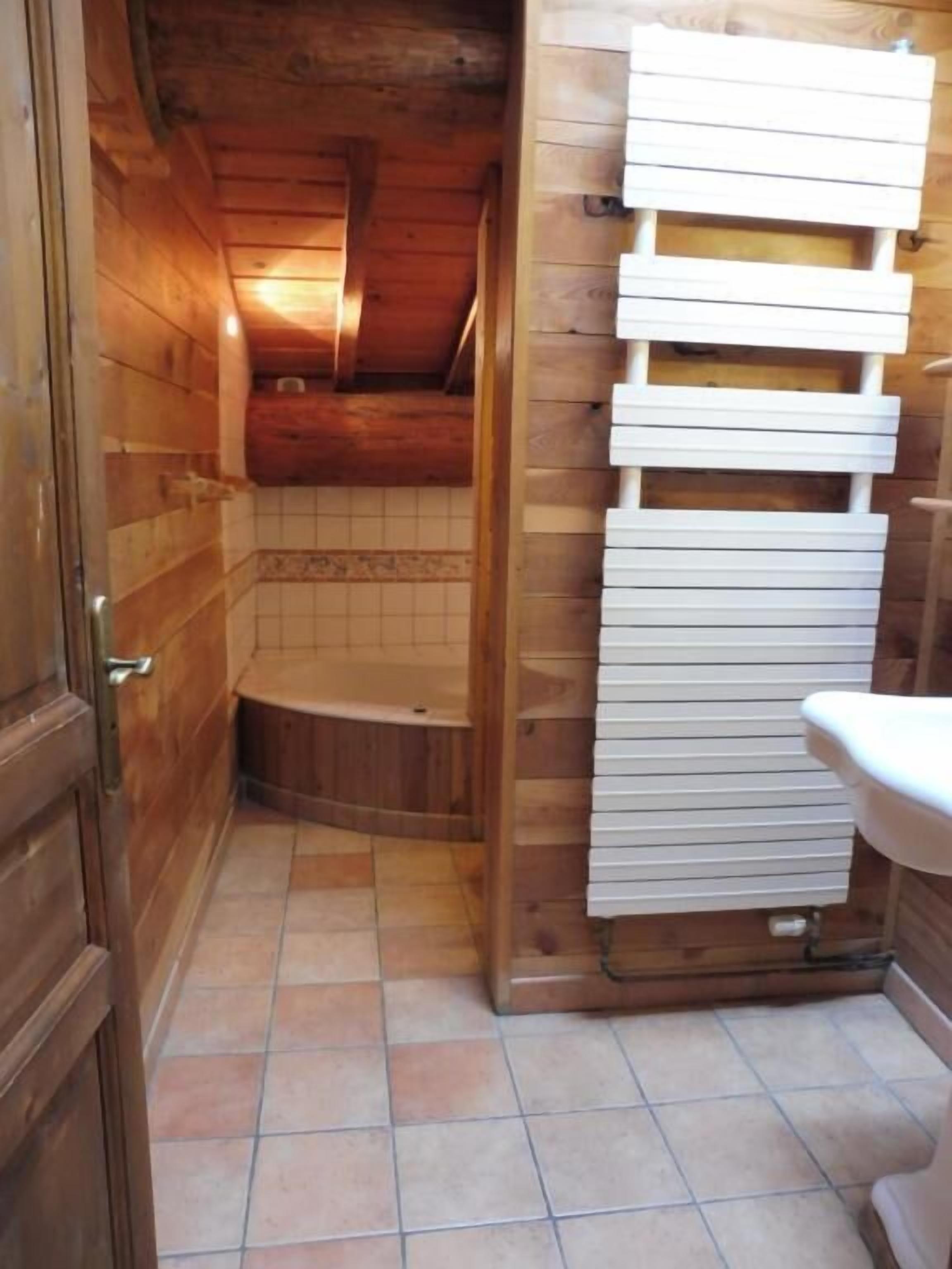 Un intérieur en bois avec un sol carrelé, un évier blanc et une porte en bois.
