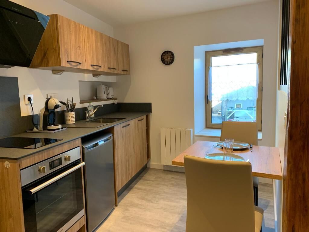 Une cuisine compacte avec des meubles en bois, un four encastré et une fenêtre donnant sur l’extérieur.
